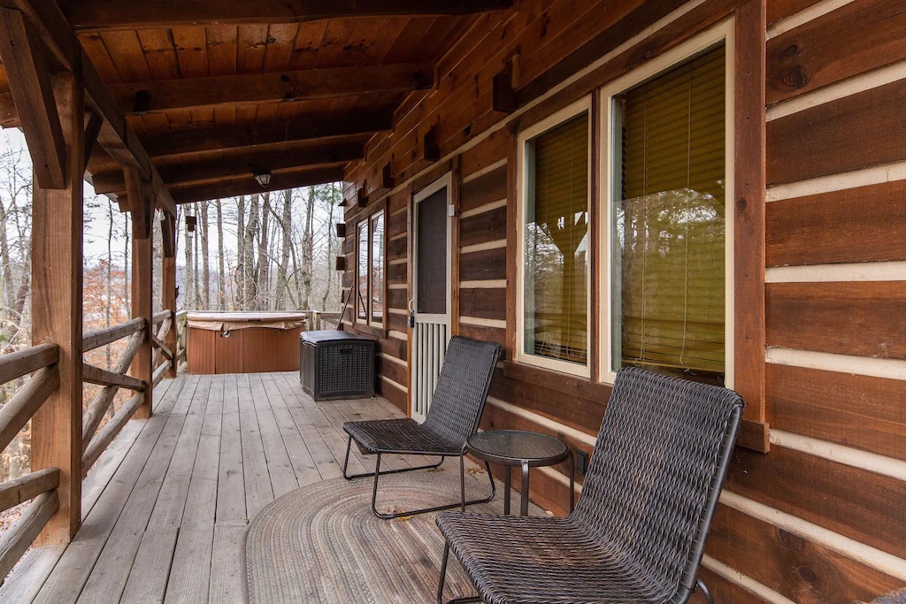 A wooden deck featuring a hot tub at the far end and seating along the covered porch area