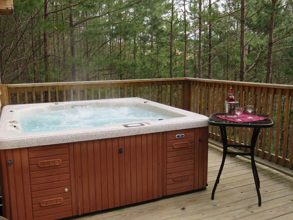 One of the cabins with a hot tub in Kentucky with warm water and a table with wine and glasses