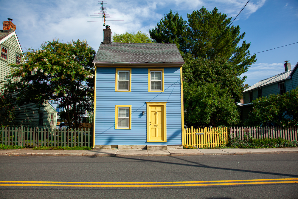 Isolated exterior image of a well maintained civil war era traditional American House. the house is blue and yellow