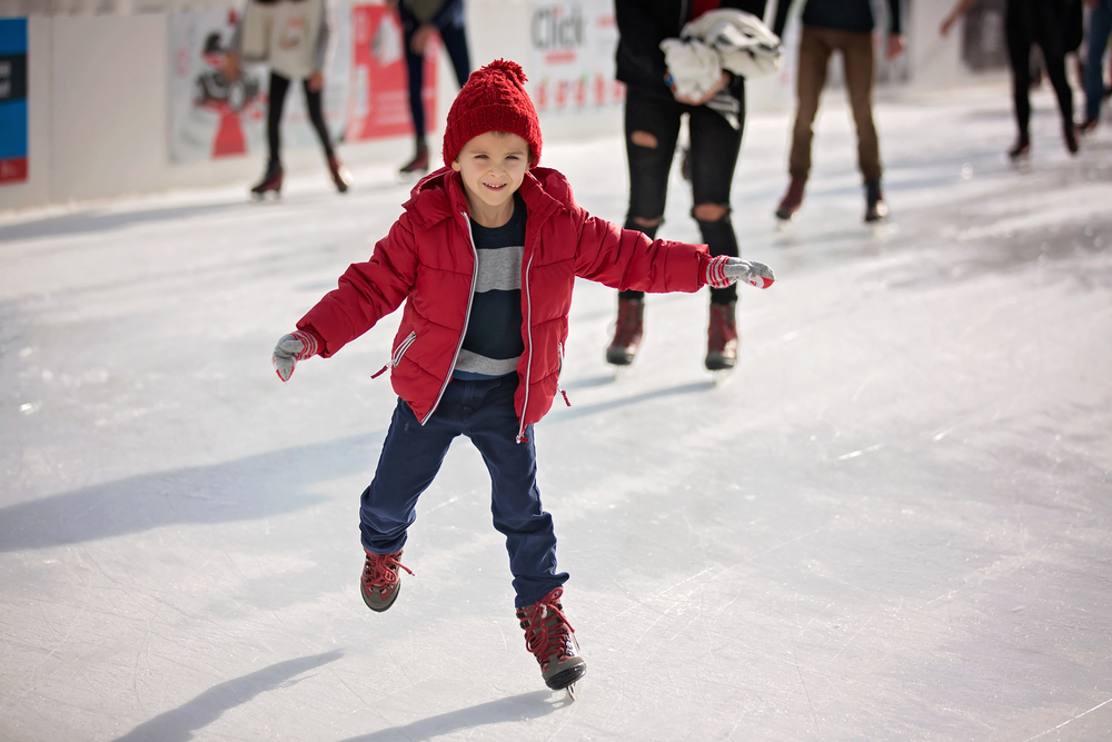 a little boy in a red hat and red jacket ice staking