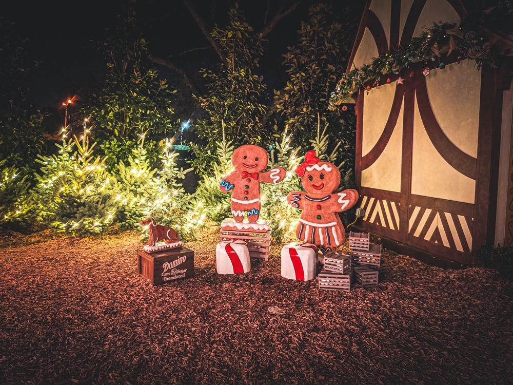 Gingerbread people in front of a decorated house and lighted Christmas trees at the Dallas Arboretum's 12 days of Christmas. 