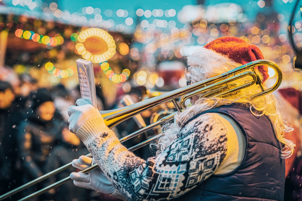 A jazz musician dressed as Santa Claus playing the trombone in the Dallas Holiday Parade, one of the best things to do for Christmas in Dallas. 