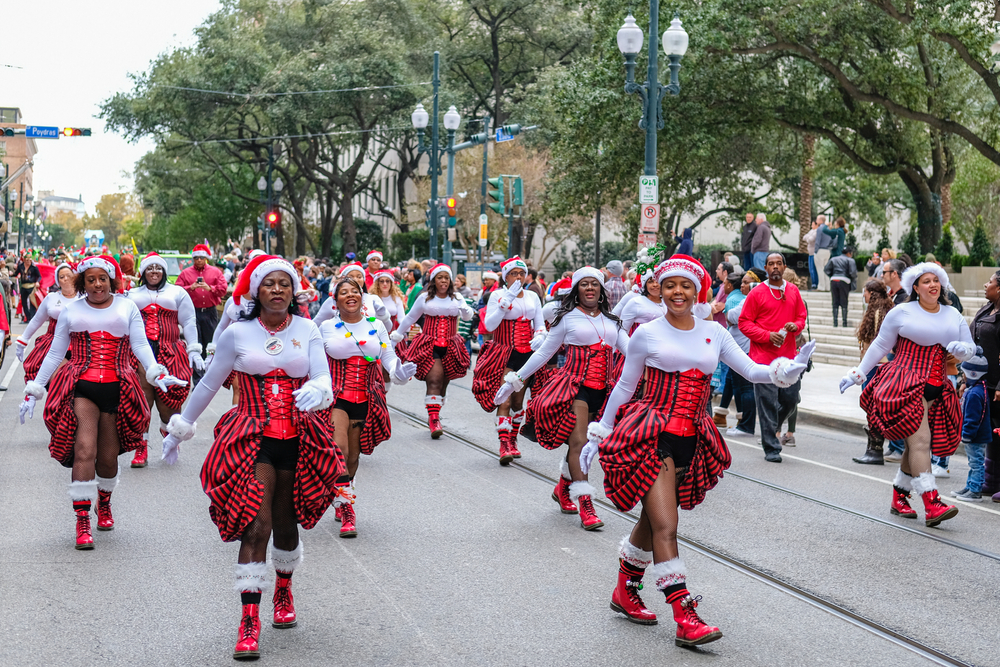 women walk the street in christmas attire for a parade in new orleans, they are wearing santa hats 