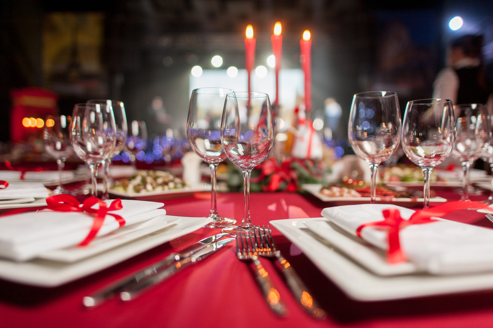 a table is set for christmas dinner, there are plates, glasses, silverware, and candles