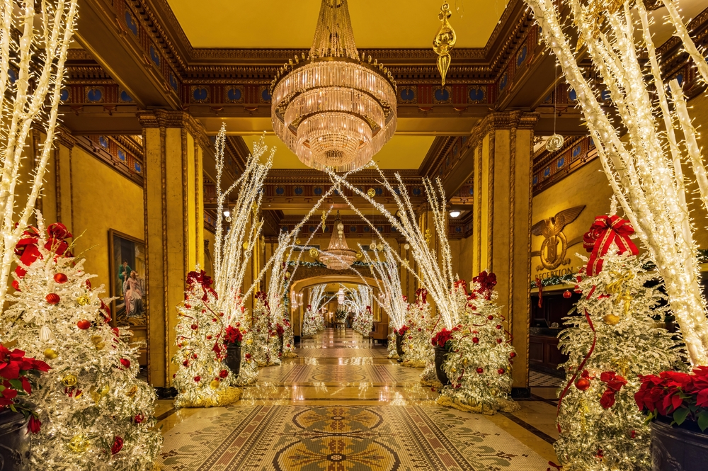 hotel lobby decorated for christmas in new orleans, chandeliers hang from the ceiling and the decorations are to the sides of the entry hallway 