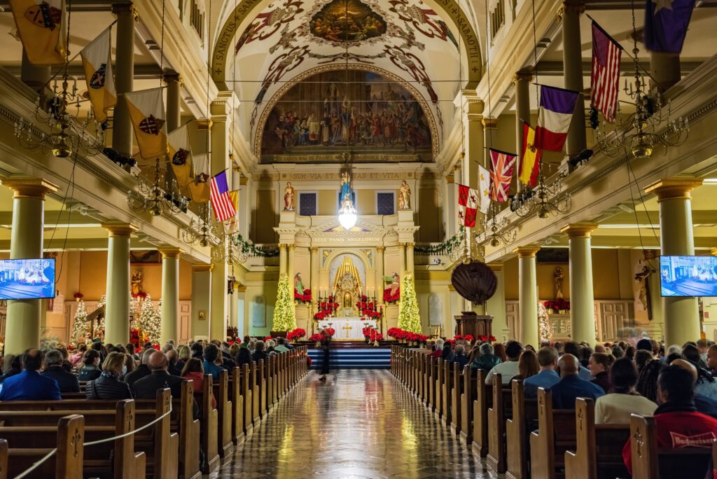 inside of the st louis cathedral during christmas in new orleans, trees are inside as well as a lot of people there to attend midnight mass