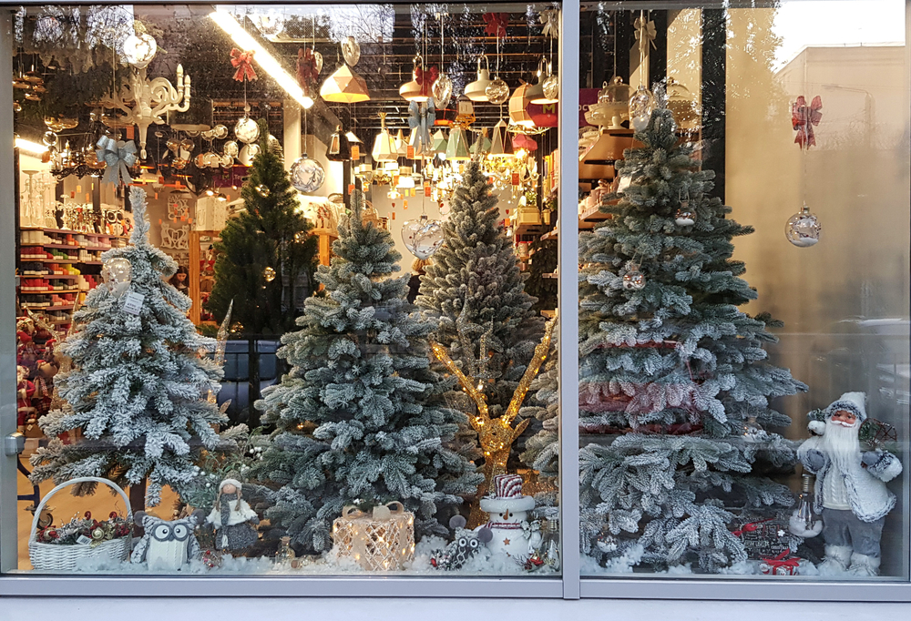a holiday window display with Chritmas trees frosted with snow and ornaments hanging from the ceiling