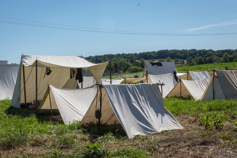numerous white war tents set up in a field at monocracy national park during the day with clear skies 