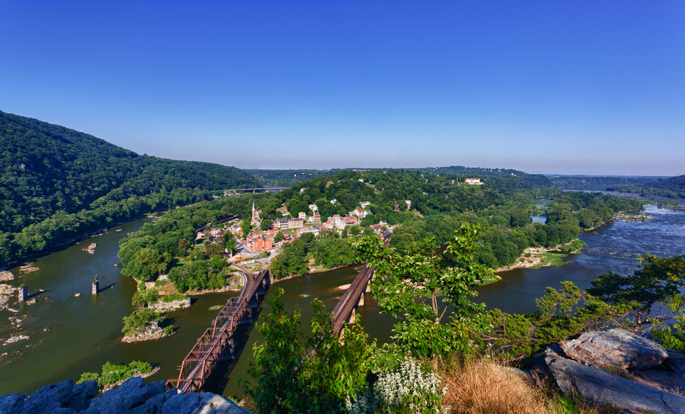view from above harpers ferry, one of the best national parks in Maryland, with two bridges and a small town surrounded by water  
