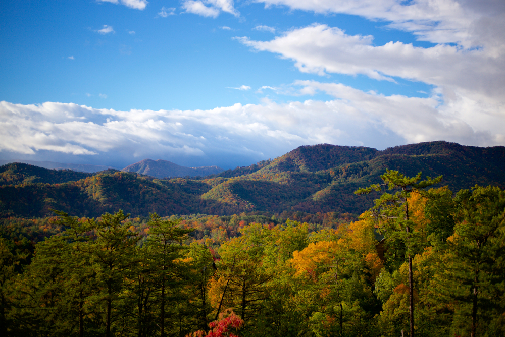 mountains on a bright sunny day, some clouds in the sky, trees have autumn leaves, blue ridge-a town with good tubing in georgia 