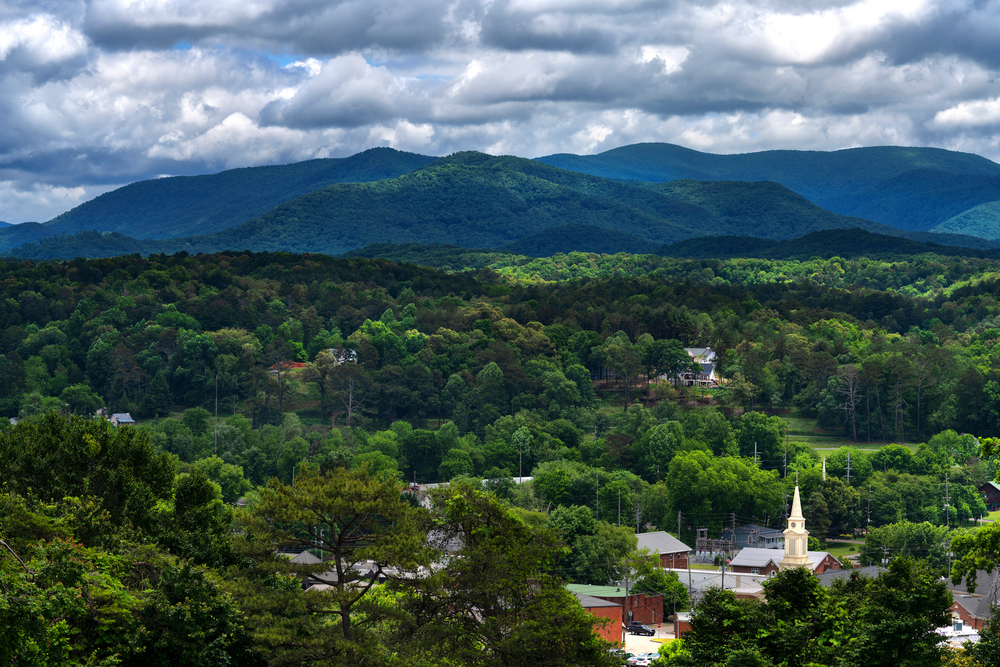 a great town for tubing in georgia, trees and mountains in the photo, buildings can be seen between the trees, cloudy day 