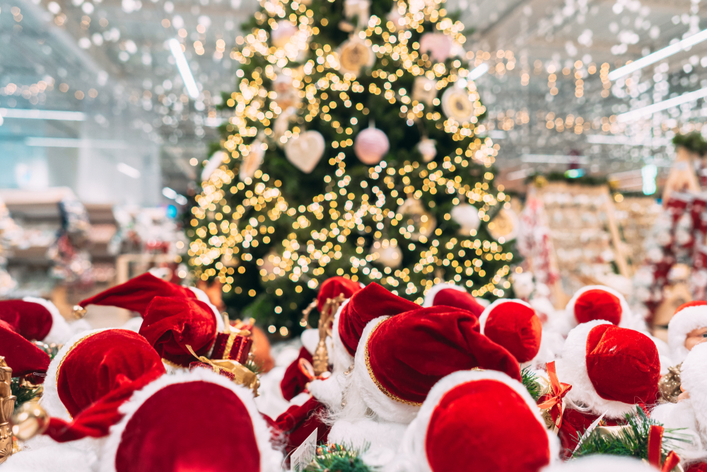 a gathering of people wearing santa hats watching a glowing christmas tree!