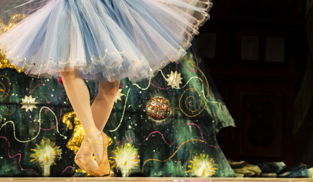 a ballerina's dancing feet while wearing a blue white dress in front of a Christmas tree