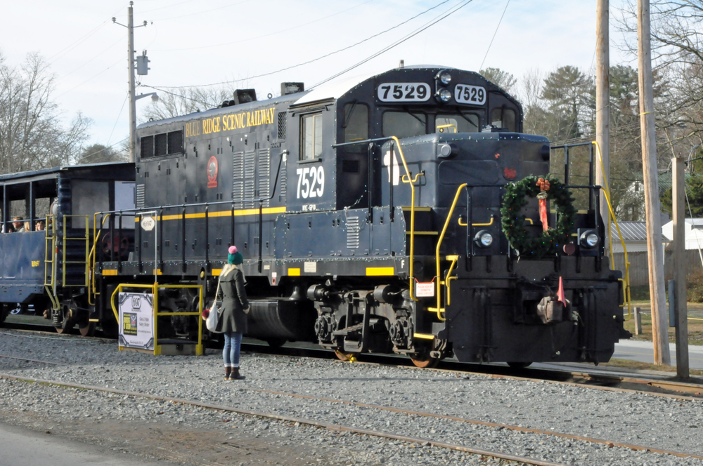 A vintage train car with an evergreen wreath on its front pulls into Blue Ridge, one of the best Christmas towns in Georgia.