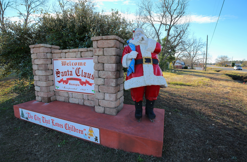 A statue of Santa Claus stands on the welcome sign of Santa Claus, GA, one of the best Christmas towns in Georgia.
