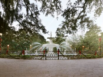 A large fountain is decorated with garland and bows in Savannah, one of the best Christmas towns in Georgia.
