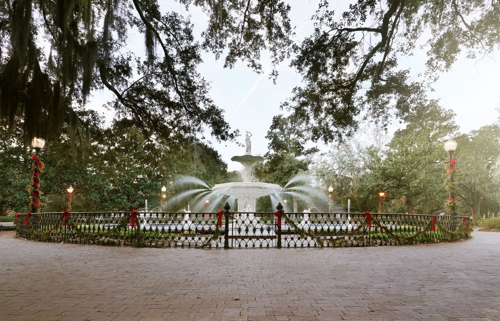 A large fountain is decorated with garland and bows in Savannah, one of the best Christmas towns in Georgia.