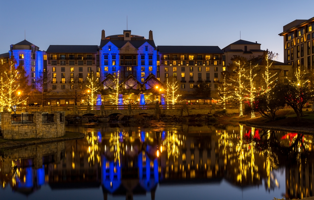 a view of some beautiful buildings off of a small body of water, decorated wth holiday twinkle lights and coloured LED displays to celebrate the season!