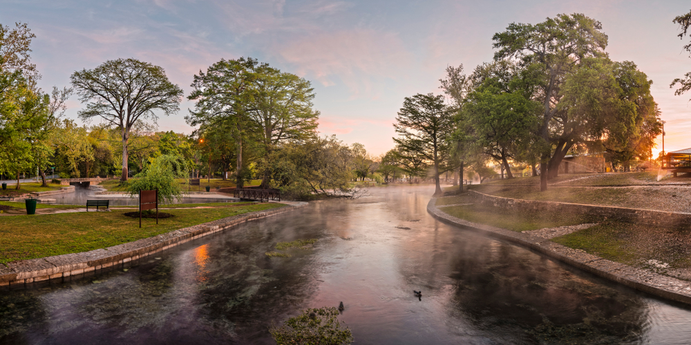 a park with a river illuminated by the setting sun, with gorgeous trees and landscaping to highlight the beautiful surroundings!