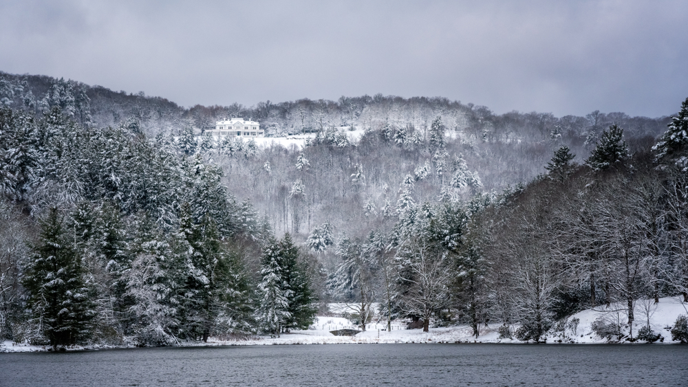 one of the best christmas towns in north carolina, a wintery scene of a lake and mountains covered in snow