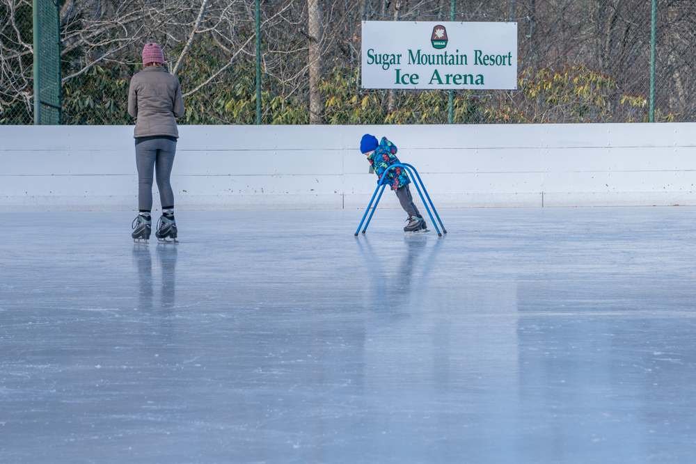 two people ice skating on an ice skating rink at the sugar mountain resort ice arena 