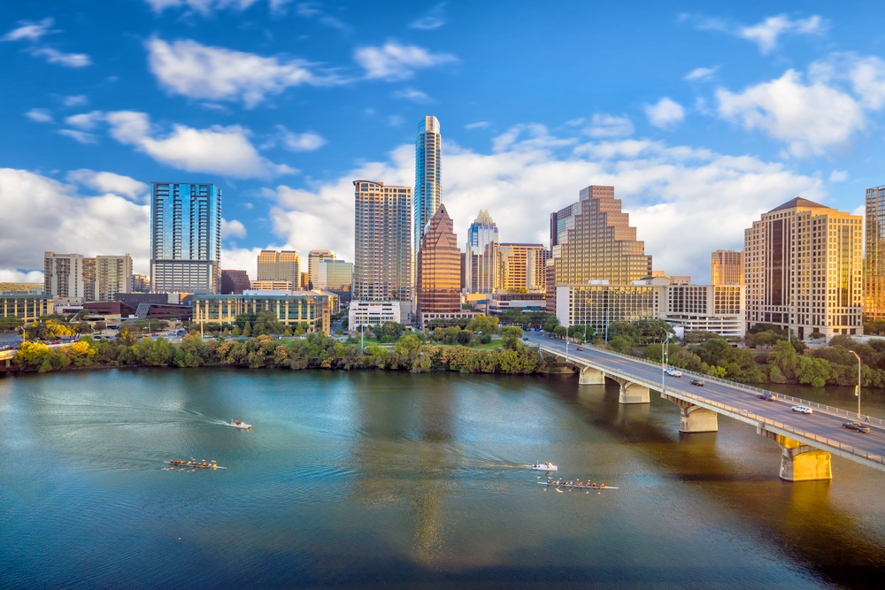 The skyline of Austin on a sunny day, where people living in Texas row boats along the river.