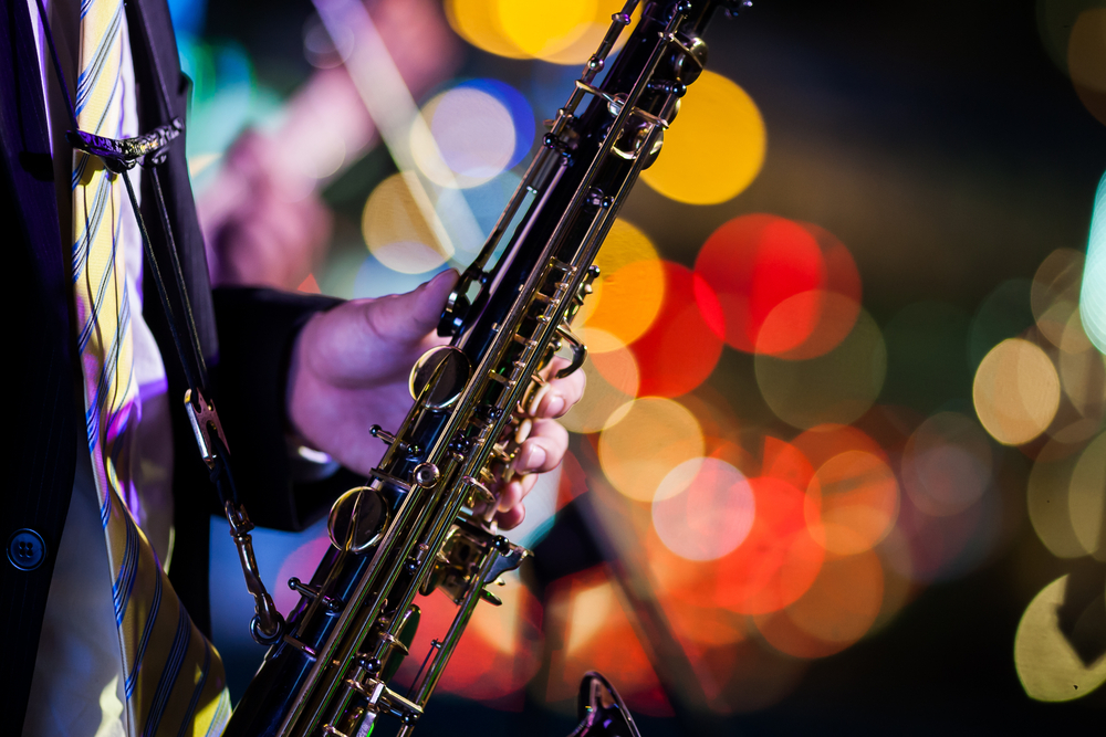 Saxophonist playing their instrument with Christmas lights in the background at the Joy to the World jazz concert in Aiken SC.