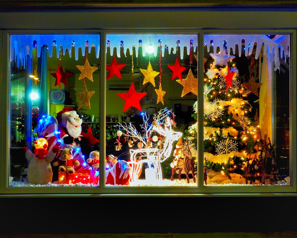 A festive window display on Main Street in Greenville with Santa, reindeer, a Christmas tree, fake snow, hanging stars and Christmas bears!