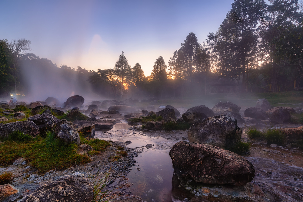 steam rising up from mossy hot rocks featured in arkansas' hot springs national park at dusk, one of the best east coast national parks