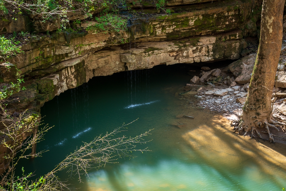 green water of a cave system at one of the east coast national parks under a cliff that is brown