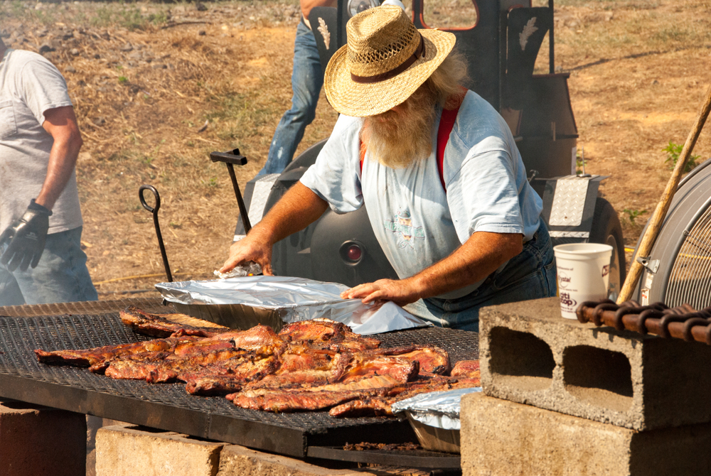 Older man outside grilling ribs at a local fair in Black Mountain, NC showing the extra large grill.