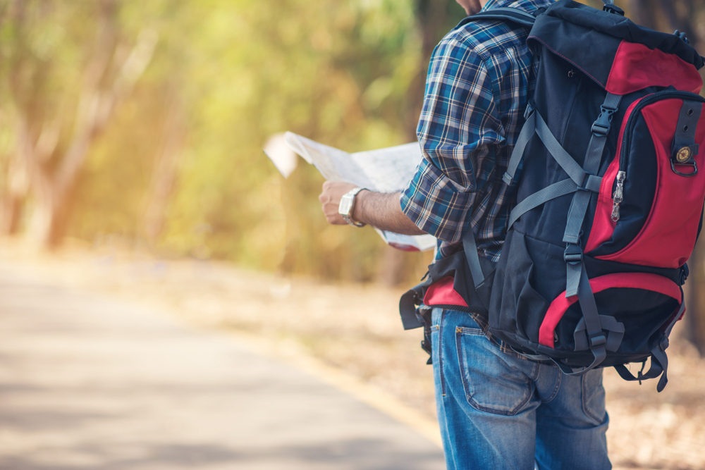 Close up of a Young Man Traveler with backpack relaxing outdoor as he reads the map