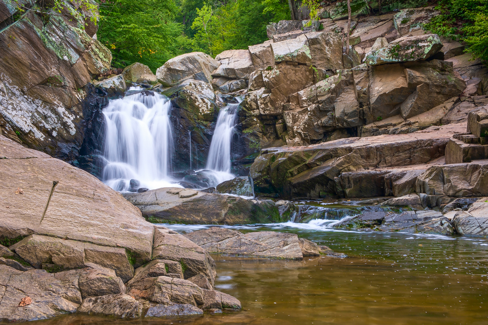 a cool arrangement of shelving rocks filling gap between the waterfall and forest, making a small oasis perfect for exploring and taking a quick dip on a nice hike!