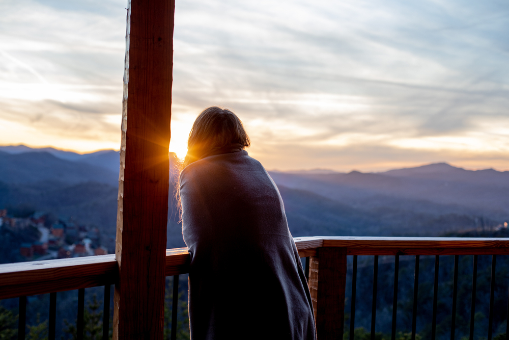 Woman wrapped in blanket on her balcony overlooking a small town in Tennessee. 