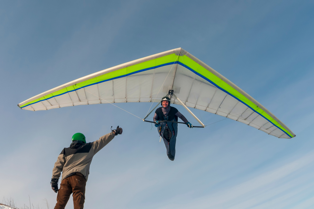 someone getting ready to take off hand gliding in the look mountains. the helper is giving a thumbs up 