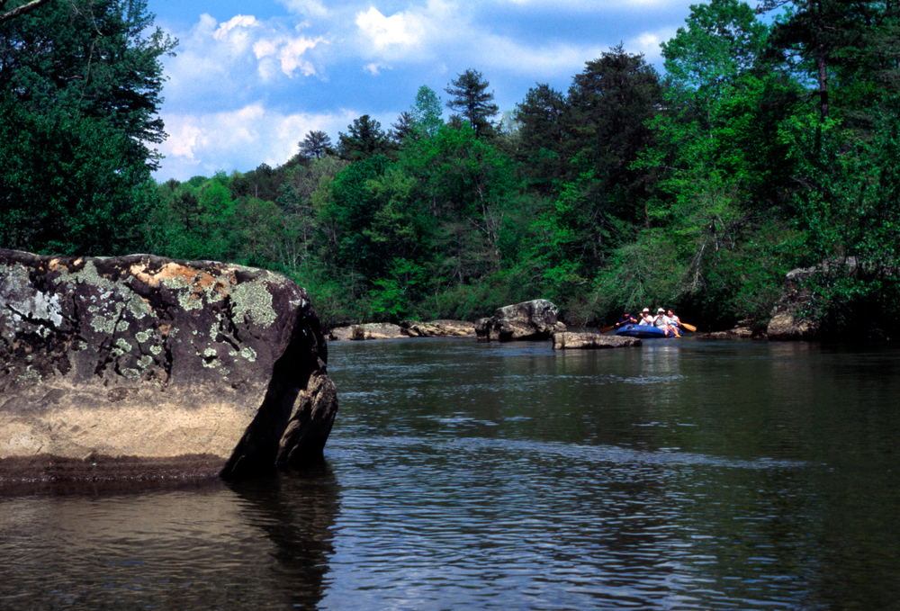 the view from the little river canyon preserve with people rafting in the water and beautiful green trees in the back round 