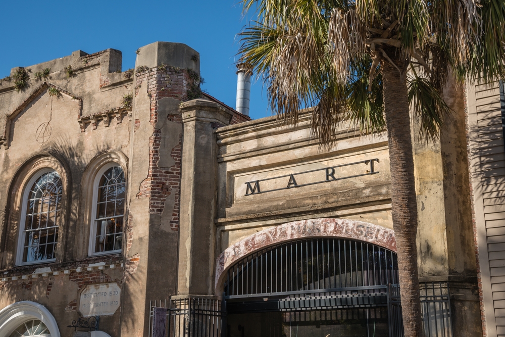 Front facade of the Old Slave Mart Museum with a palm tree.