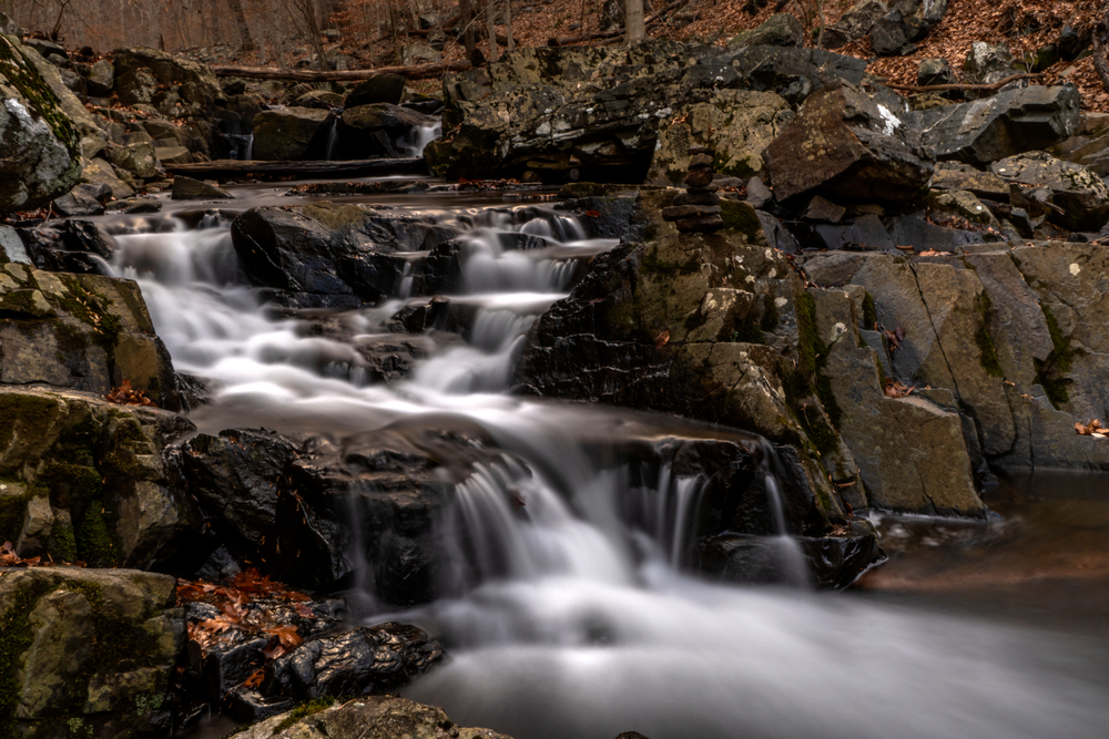 A close up view of the bottom of a multi-steeped waterfall with tons of rocks