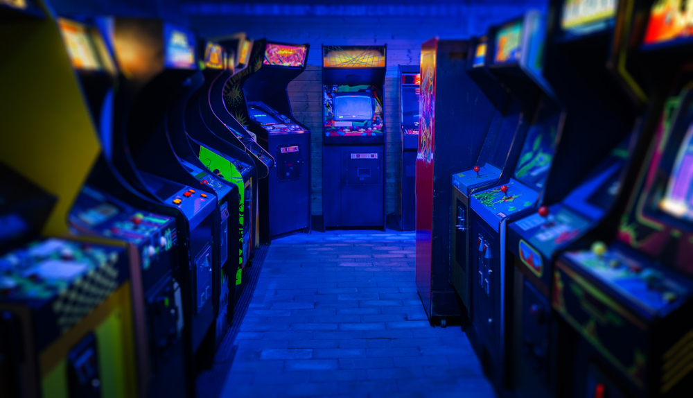 a bunch of retro video games inside the Rudy arcade. it is lit with neon blue color and about 20 different games to pick from to play 