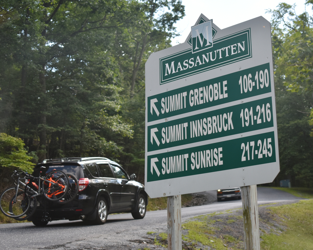 a green sign at the entrance of massanutten resort in harrisonburg vat that tells you how far away you are from the hikes 