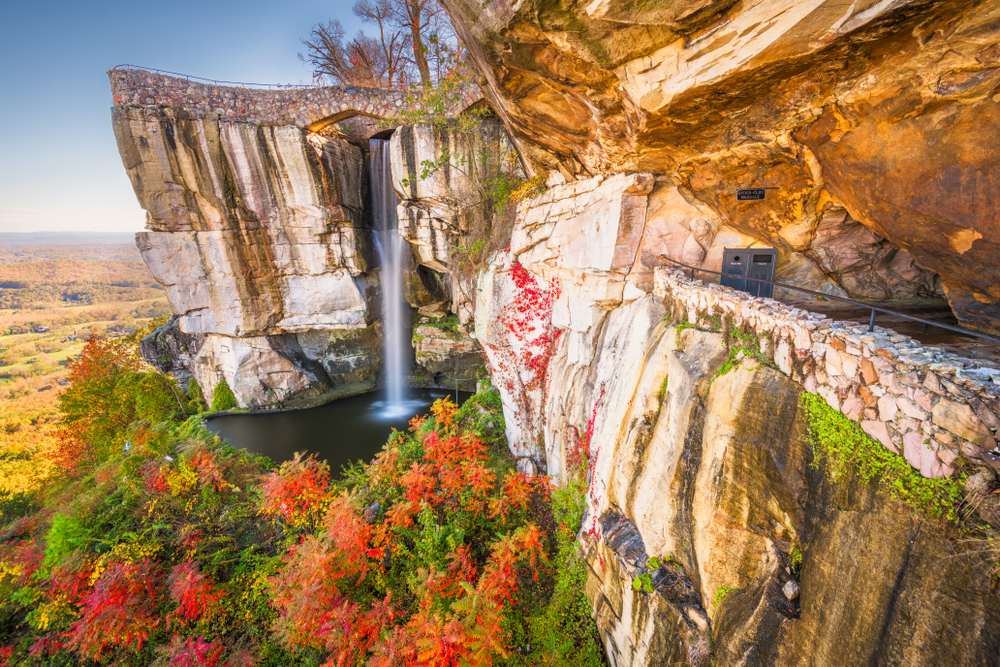 View of High Falls cascading down a rocky cliff into a pool surrounded by fall foliage.
