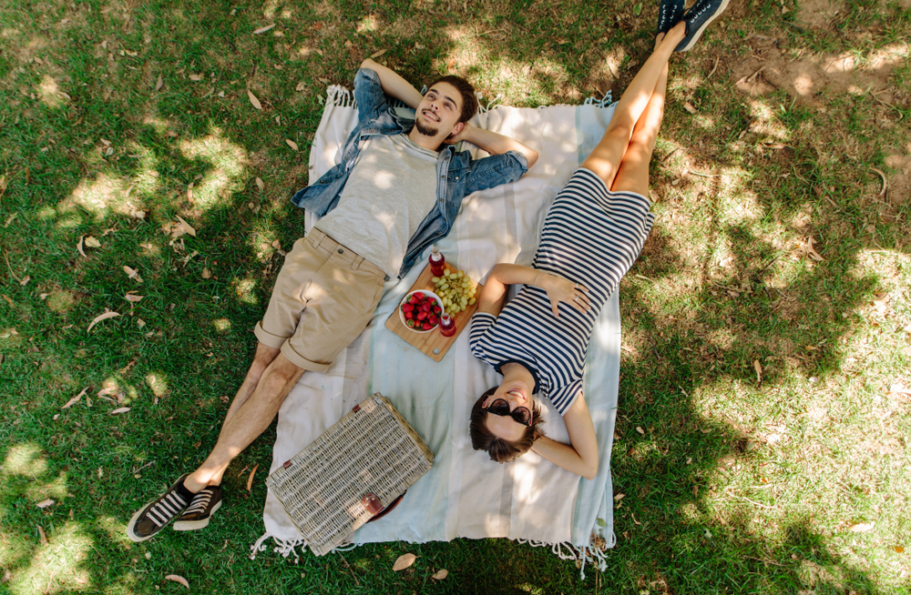 A man and woman laying on a blanket, enjoying a picnic at Cate Square Park. 