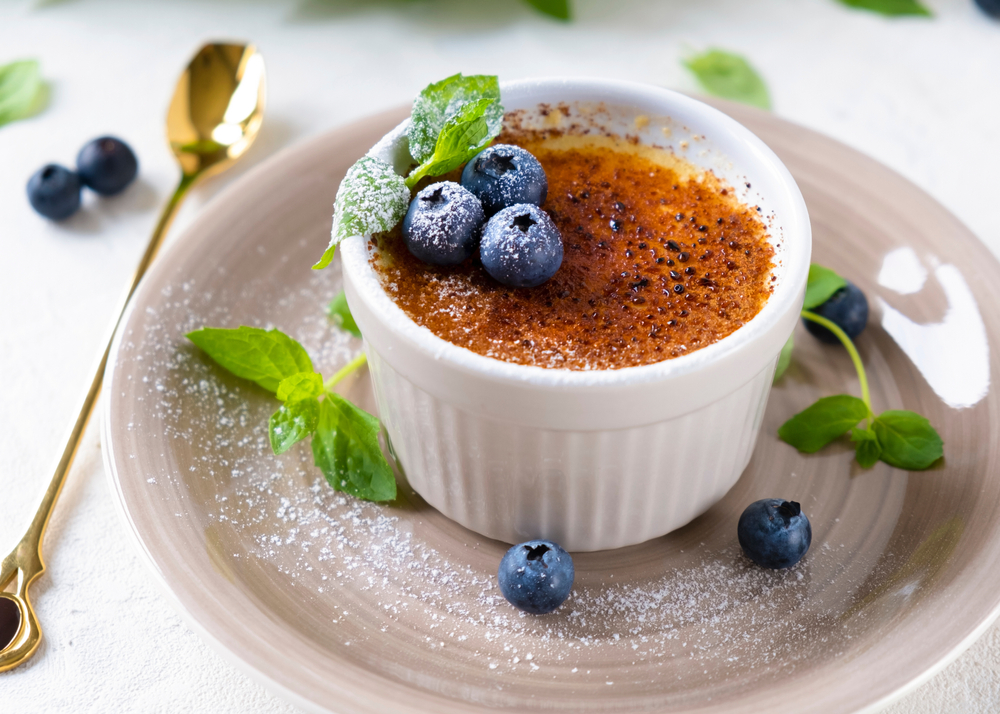 The Vanilla Crème Brûlée at One Thirteen served with berries, mint, and a gold spoon. 