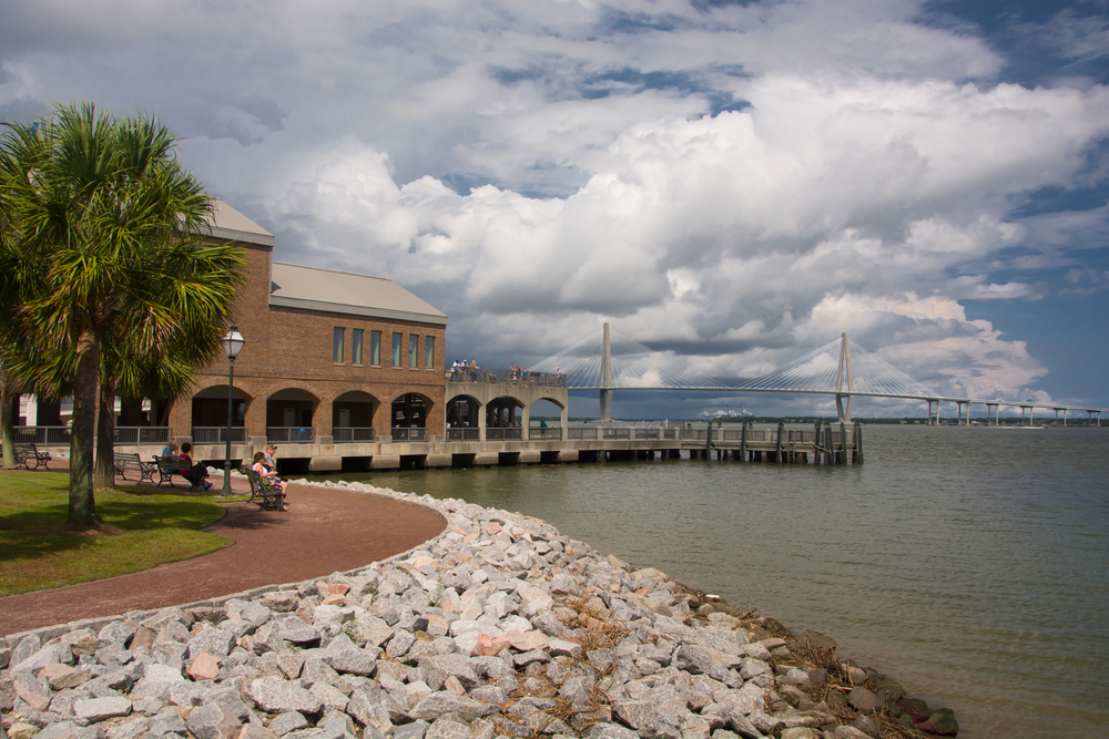 a view of Fort Sumter South Carolina on the beach with rocks and a bridge in the back round. 