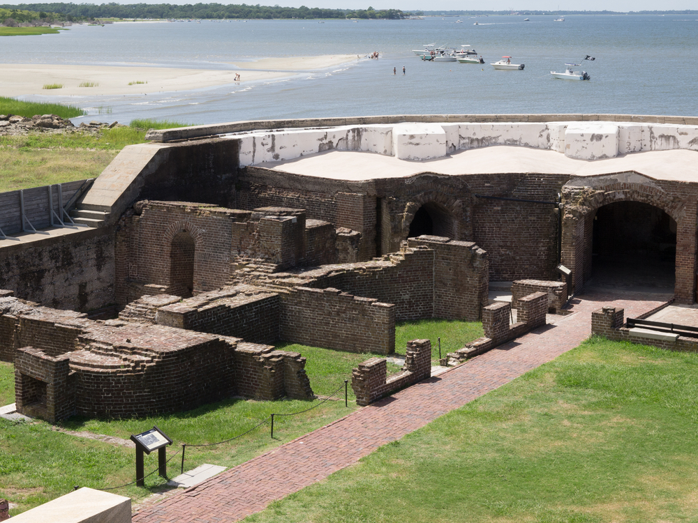 a great look at the fort from the inside. you can see the ocean full of boats in the back round and the green grass on the side. 
