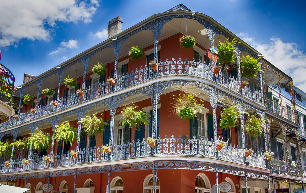 cast iron balconies on a french and spanish influences building new orleans, plants are hanging from the balconies 