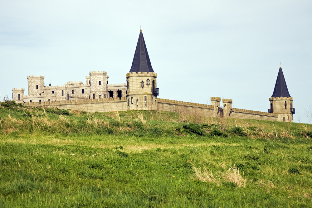a german inspired castle in a grassy field in kentucky, two large spries, a tall wall ,and an inner castle building are all there, photo taken on a cloudy day, places in the South USA that look like Europe