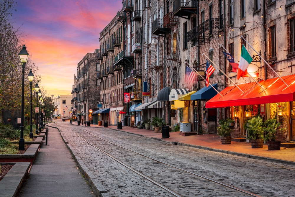 savannah georgia, one of the places in the South USA that look like Europe, a cobblestone road is in the middle and tall brick and stone buildings line the road on the right