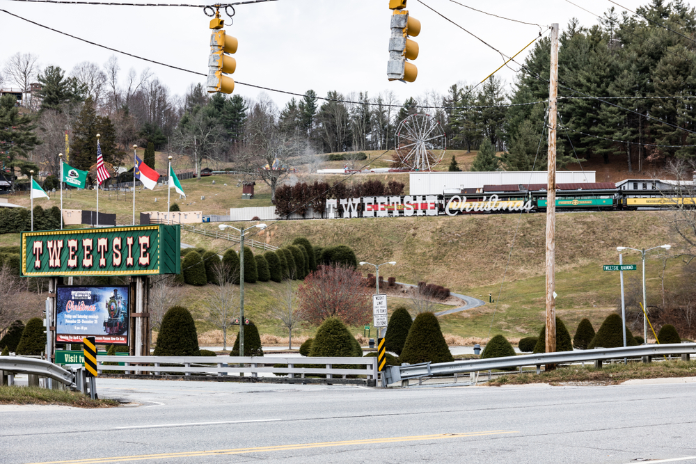 the Tweetsie Christmas train in Boone during the day with a Ferris wheel and lots of flags flying out front