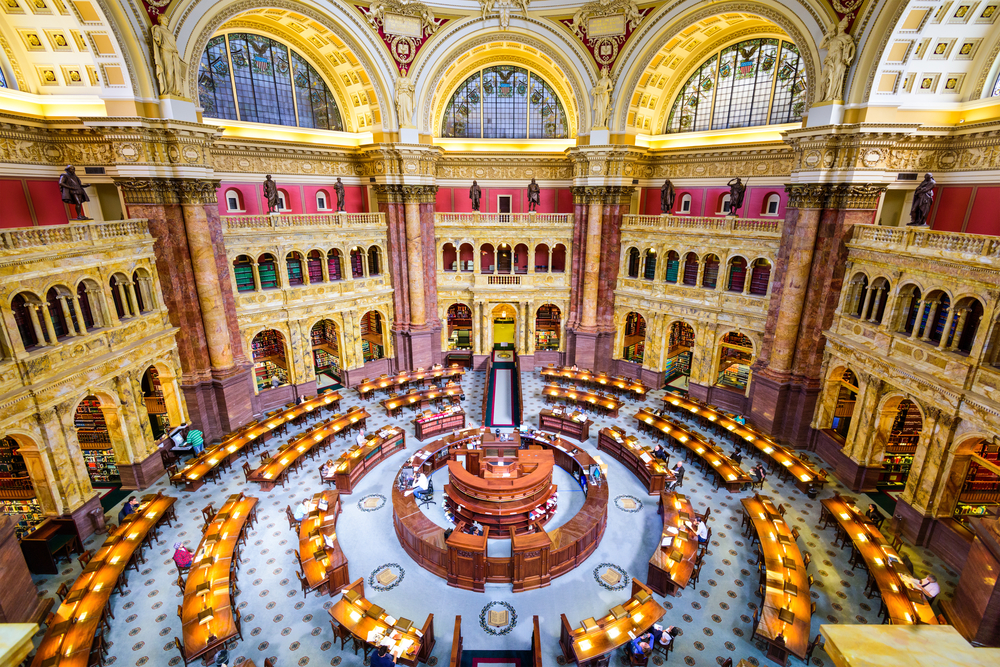 round interior of the library of congress with ornate designs on the walls and archways, tables are on the ground in a circle shape below